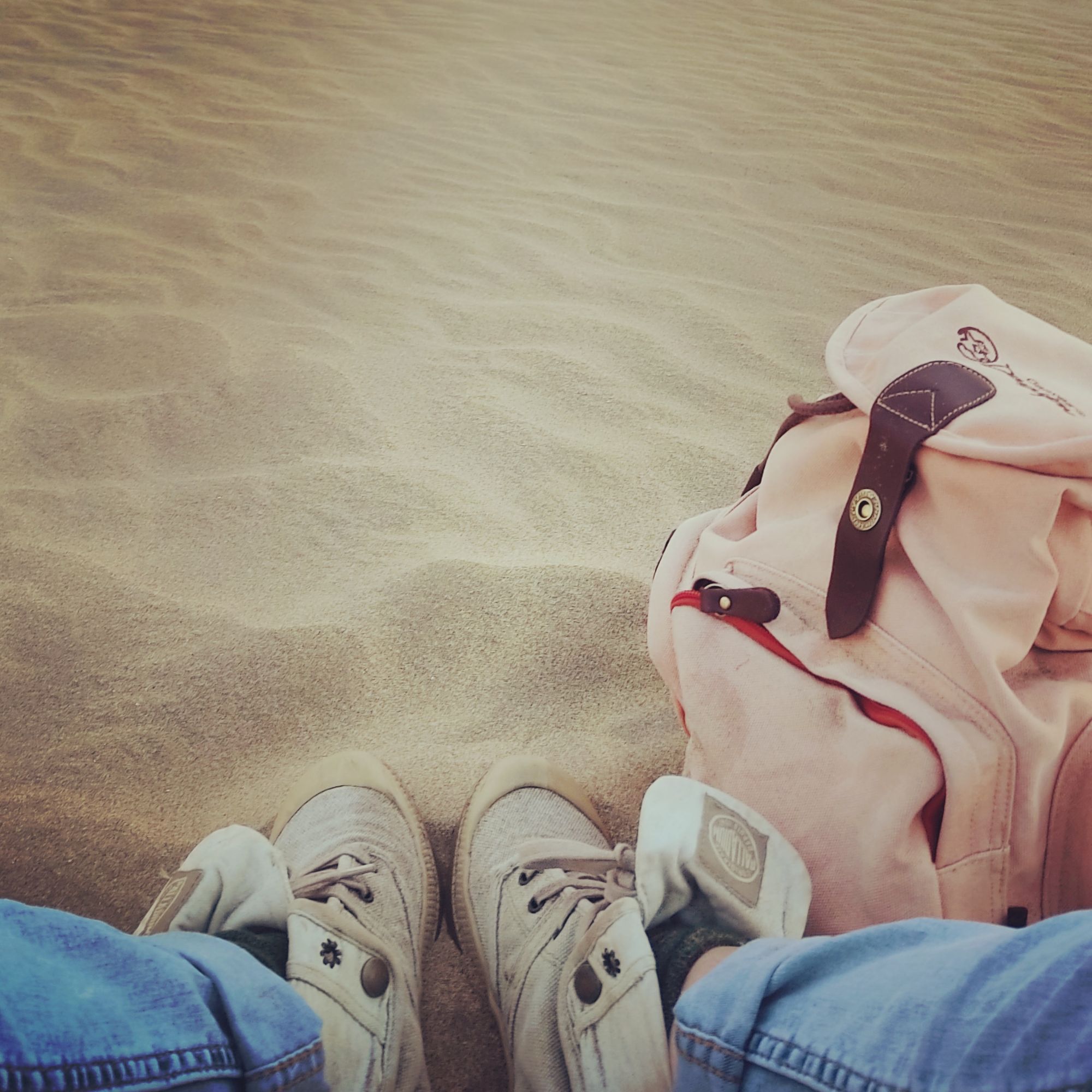 Worn travel boots and a backpack resting on rippled desert sand