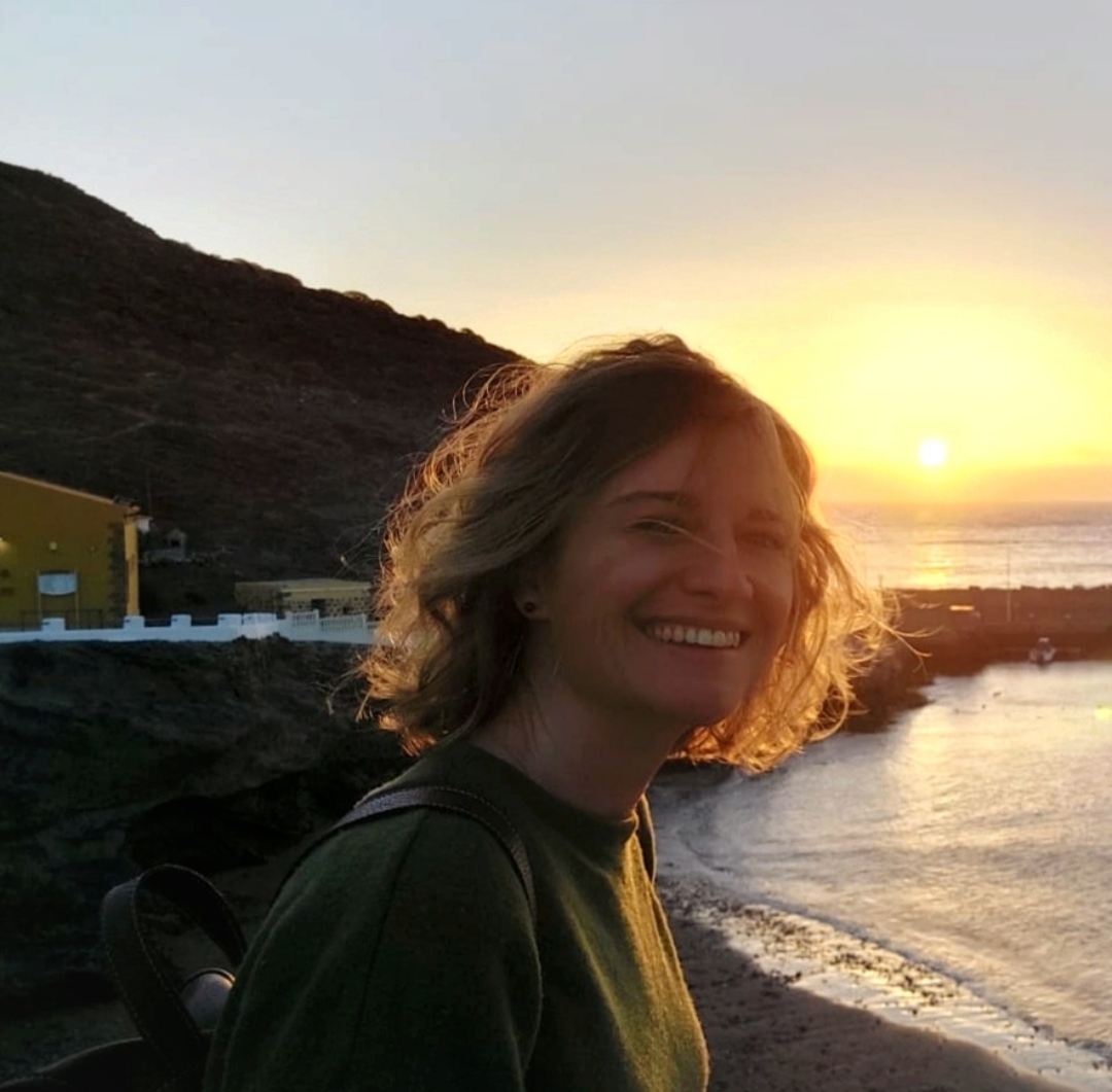 Elie smiling by the sea at sunset